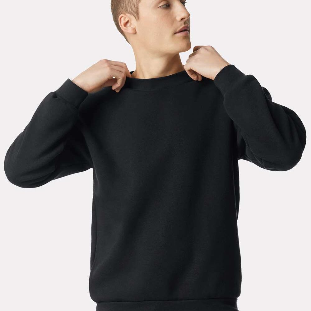 Man in a black crewneck sweater adjusting the neckline