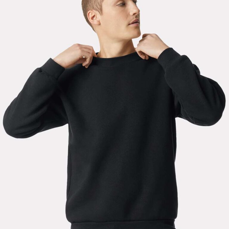 Man in a black crewneck sweater adjusting the neckline