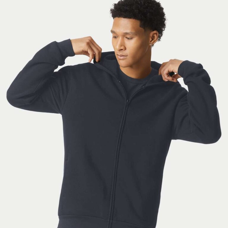 Man wearing a navy zip-up hoodie and light blue jeans