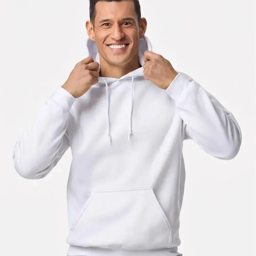 Man in a white hooded sweatshirt and blue jeans smiles while holding hoodie strings