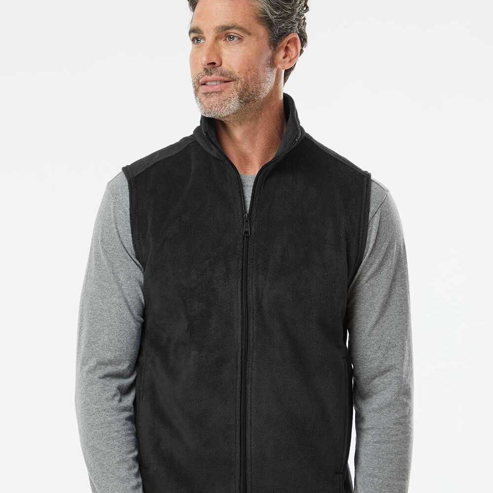 Man wearing a black zip-up fleece vest over a grey long-sleeved shirt.