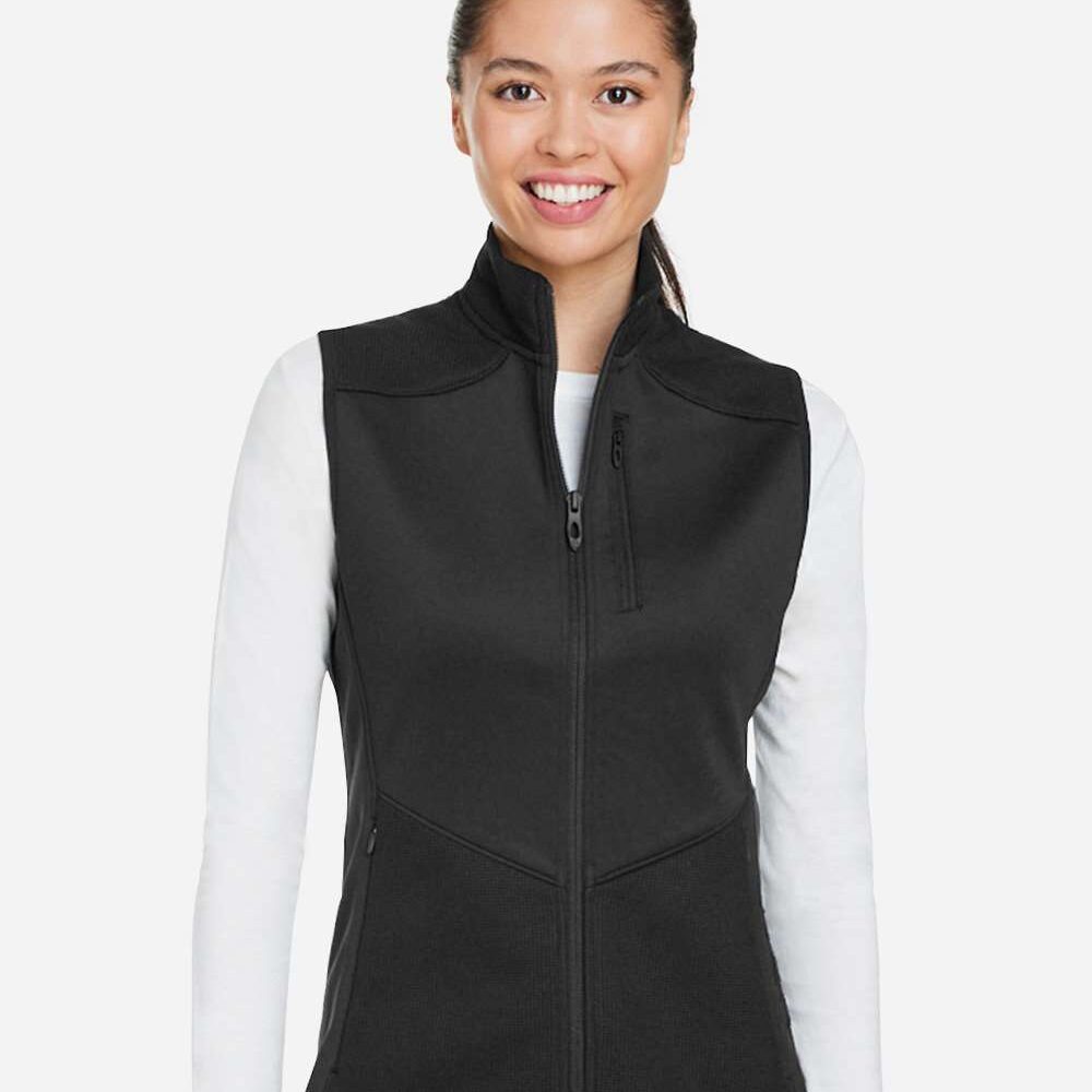 Woman wearing a black zip-up vest over a white long-sleeve shirt.