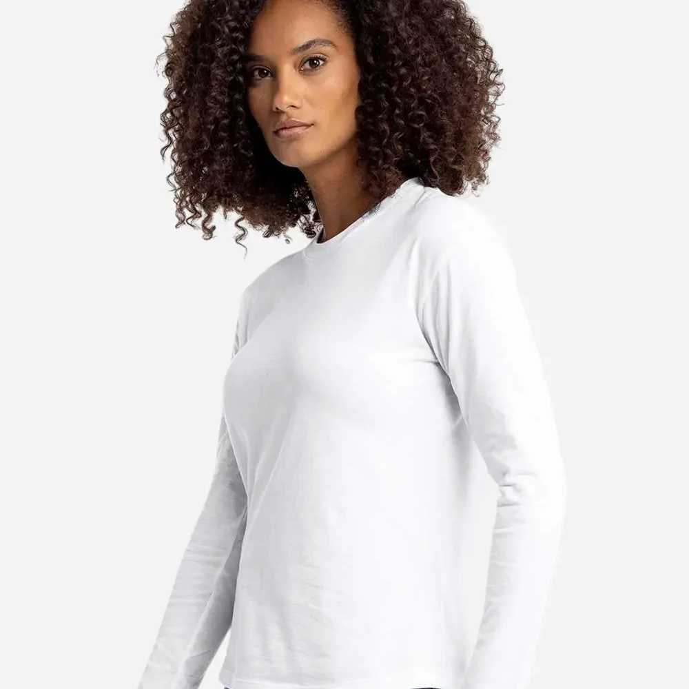 Woman in white long sleeve shirt and blue jeans, with curly dark hair