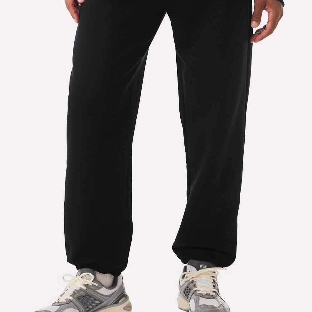 Person wearing black sweatpants and grey athletic sneakers.