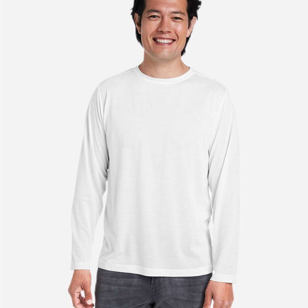 Man in white long sleeve shirt and grey jeans smiles at camera