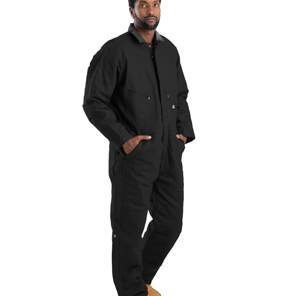 Man in black canvas work jumpsuit and tan work boots, hands in pockets