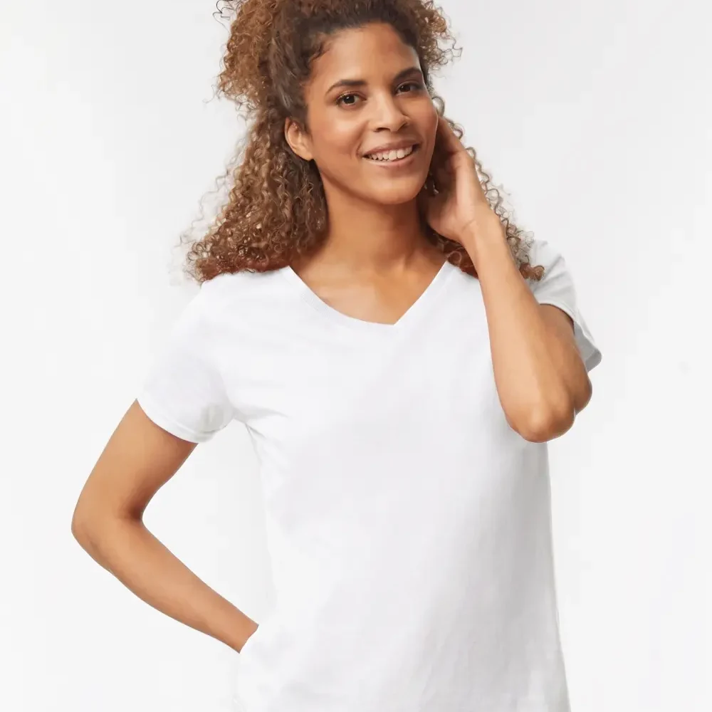 Woman wearing a white v-neck t-shirt and blue jeans, smiling and touching her hair