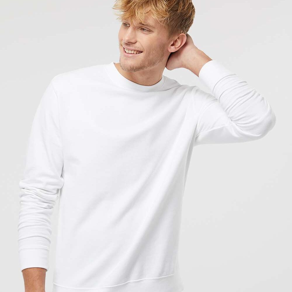 Man in white long sleeve crewneck sweatshirt and black jeans smiles.