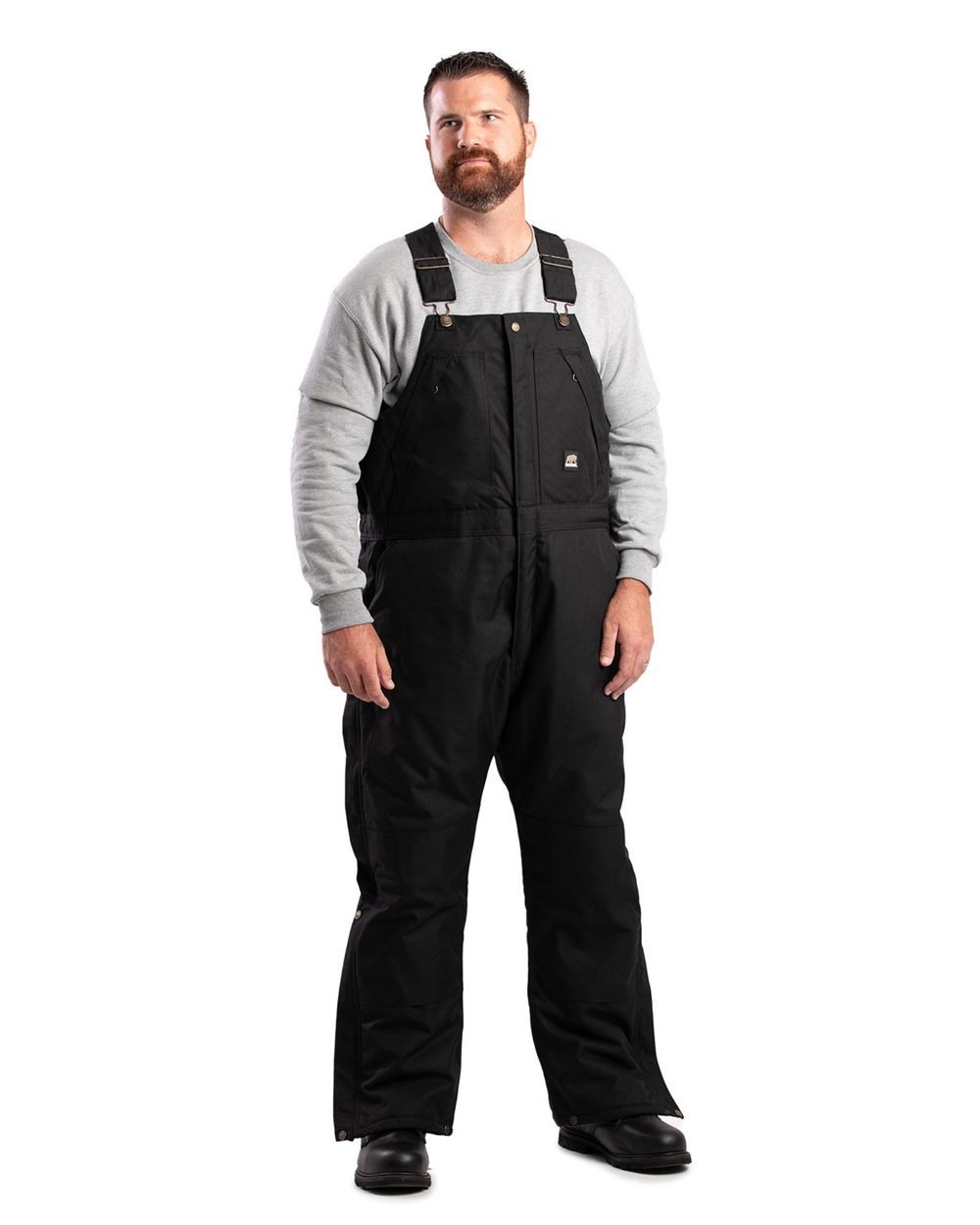 Man in black insulated bib overalls and grey sweatshirt