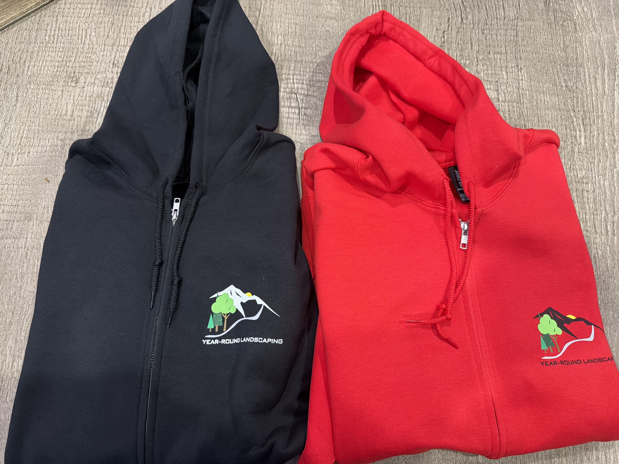 Black and red zip-up hoodies with Year-Round Landscaping logo